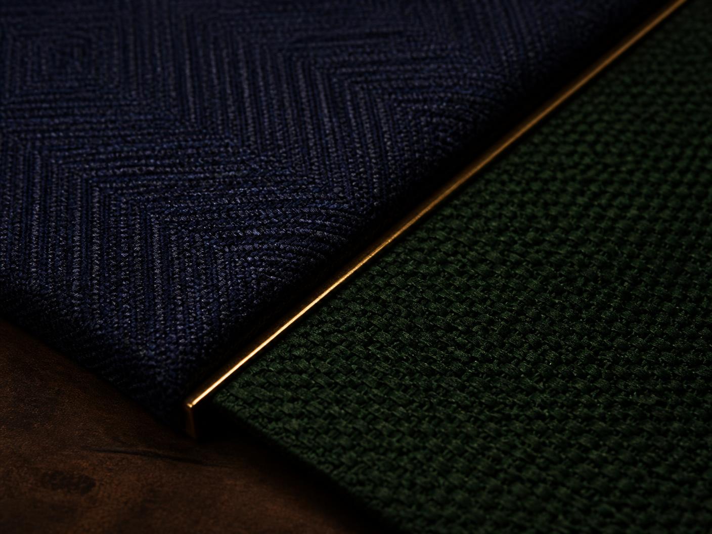 Indigo and forest green woven textiles meeting along a fine gold divider